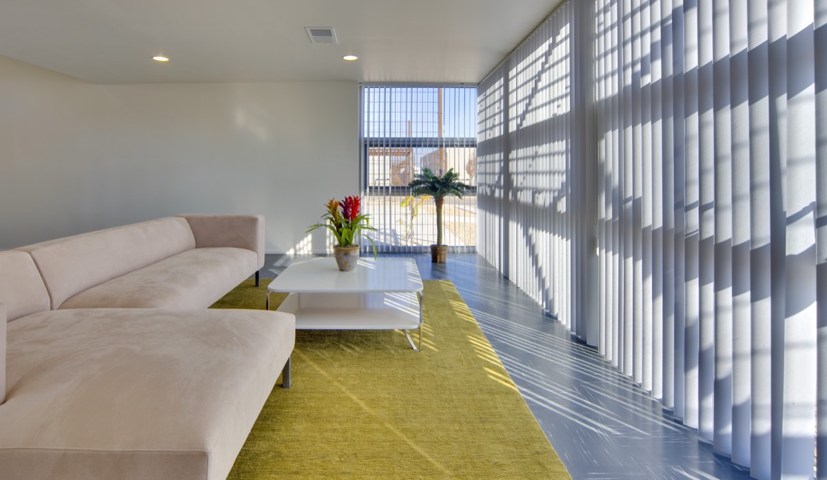 Bright community center lounge at Lo Lomas with a sectional sofa and a wall of windows